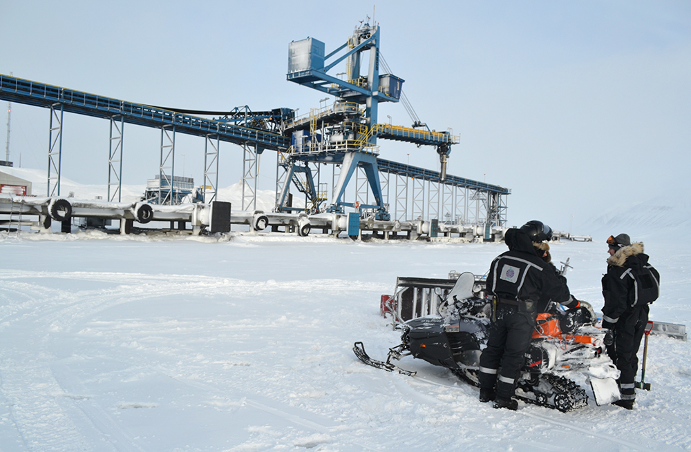 Men, snowmobile and crane in Svea, Svalbard (wintertime)