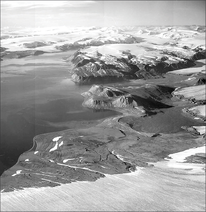 Modified oblique aerial photograph from 1938 from an altitude of 2900 m.a.s.l. above the eastern margin of Valhallfonna with a view to the south down Lomfjorden. The bay of De Geerbukta and the Fakse moraine system are located in the foreground. Source: The Norwegian Polar Institute